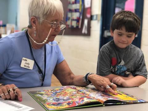 SML Good Neighbors volunteer reading to a student