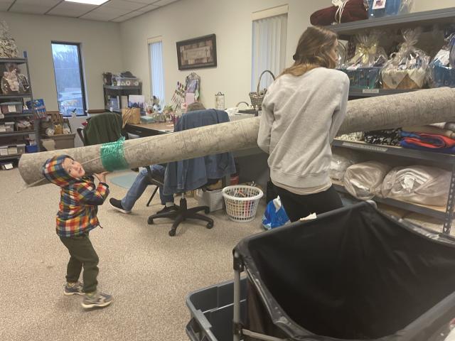 Little one helping to carry a large area rug.