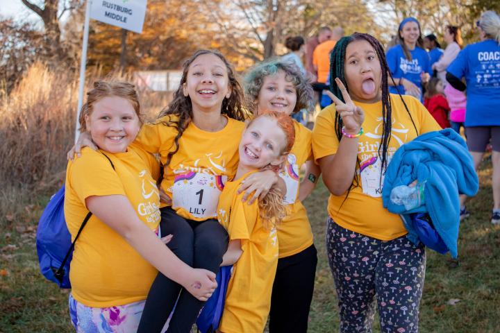 Image of gilrs ages 8-11 smiling, laughing, and having fun together at a girls on the run 5K event